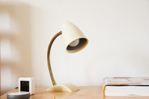 a white adjustable table lamp beside a clock