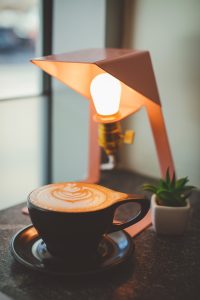 a cup of cappuccino near an Edison bulb table lamp