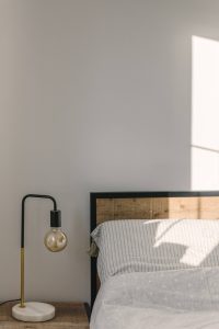 a table lamp with a metal base near a wall in sunlight