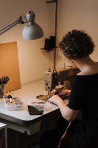 a seamstress working under an industrial-style table lamp