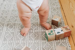 Baby Legs next to Toy Building Blocks