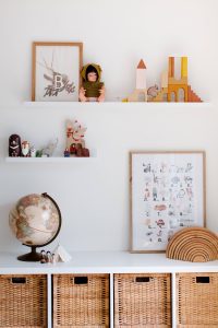 Floating shelf decorated with dolls, wooden toys and artwork